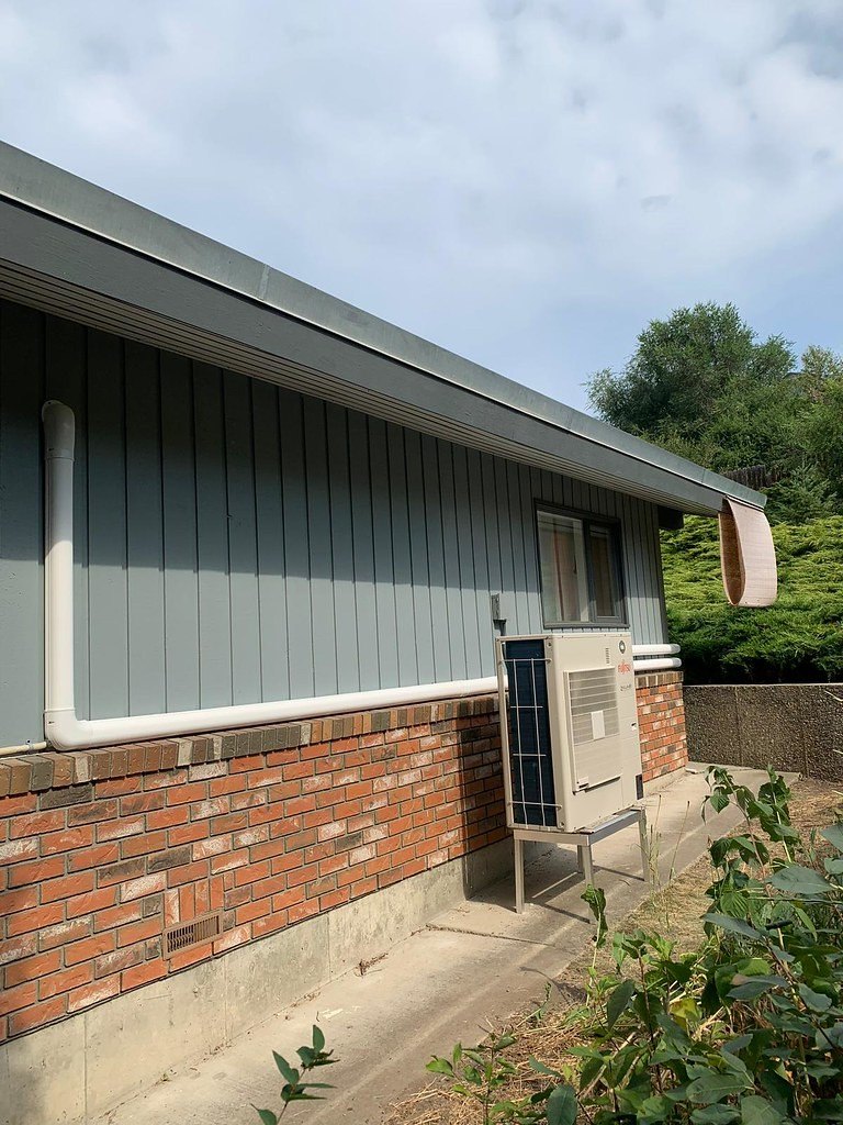 Single-story brick and siding house with an outdoor heat pump unit on the side wall
