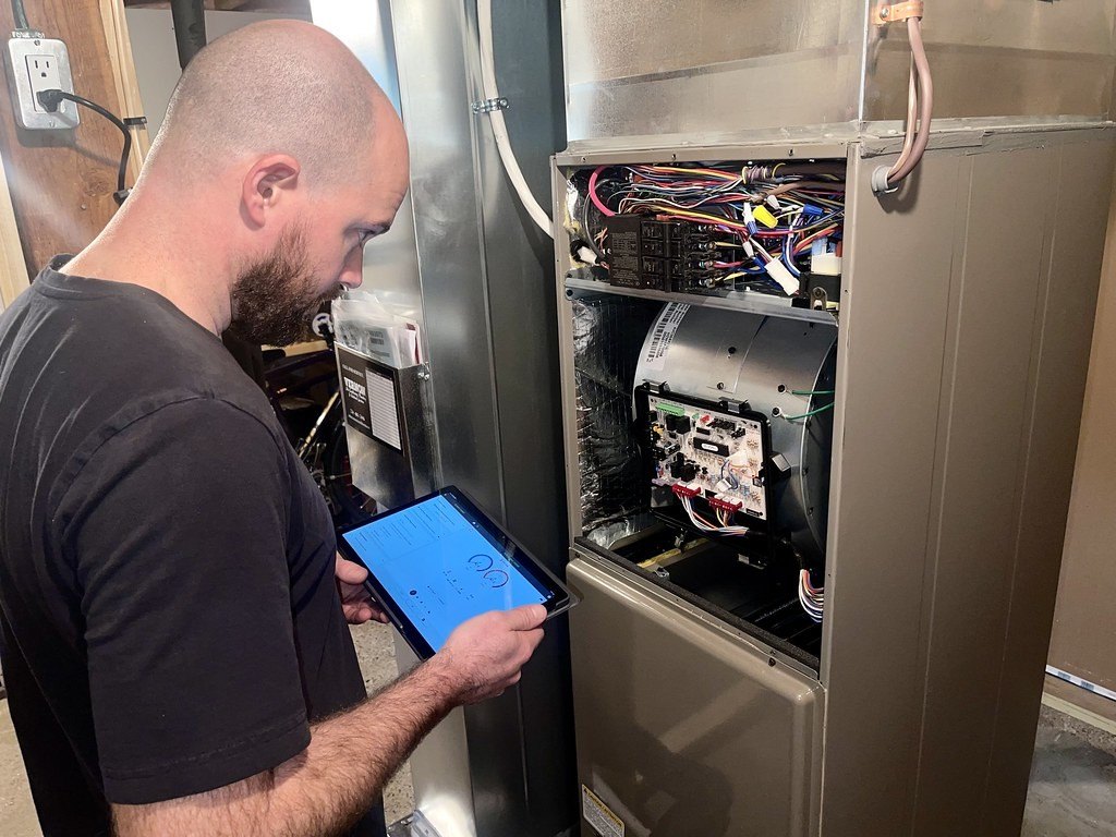 Technician checking readings on a tablet in front of an open furnace