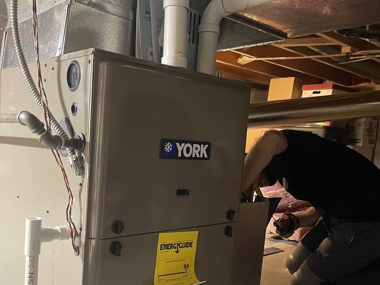 Newly installed gas furnace with the technician working behind it