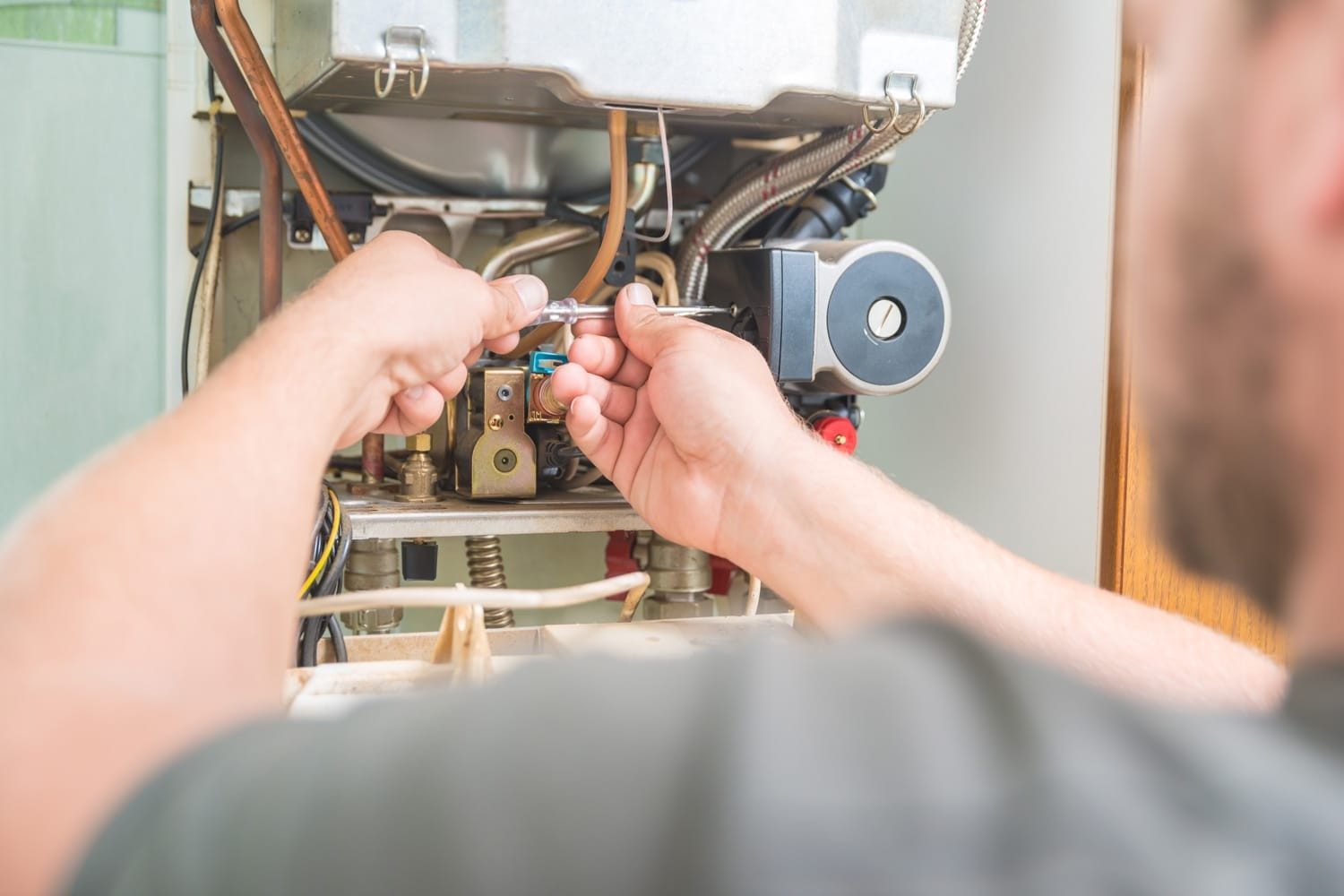 Hands adjusting the gas valve assembly inside a furnace