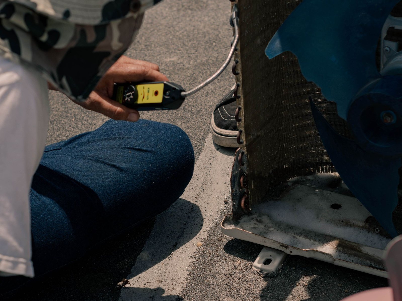 Technician running a refrigerant leak detector along an open condenser coil