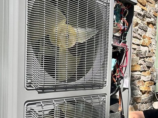 Close-up of a new two-fan outdoor unit with its control panel open during installation